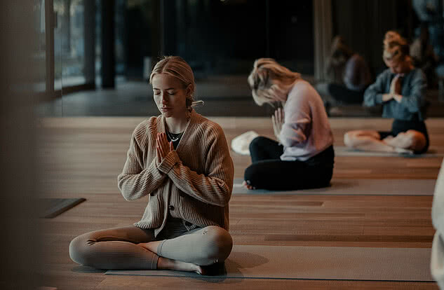 Frauen meditieren in einem stilvollen Yoga-Raum im Genussdorf Gmachl – perfekte Auszeit für einen Yoga Urlaub in Salzburg.