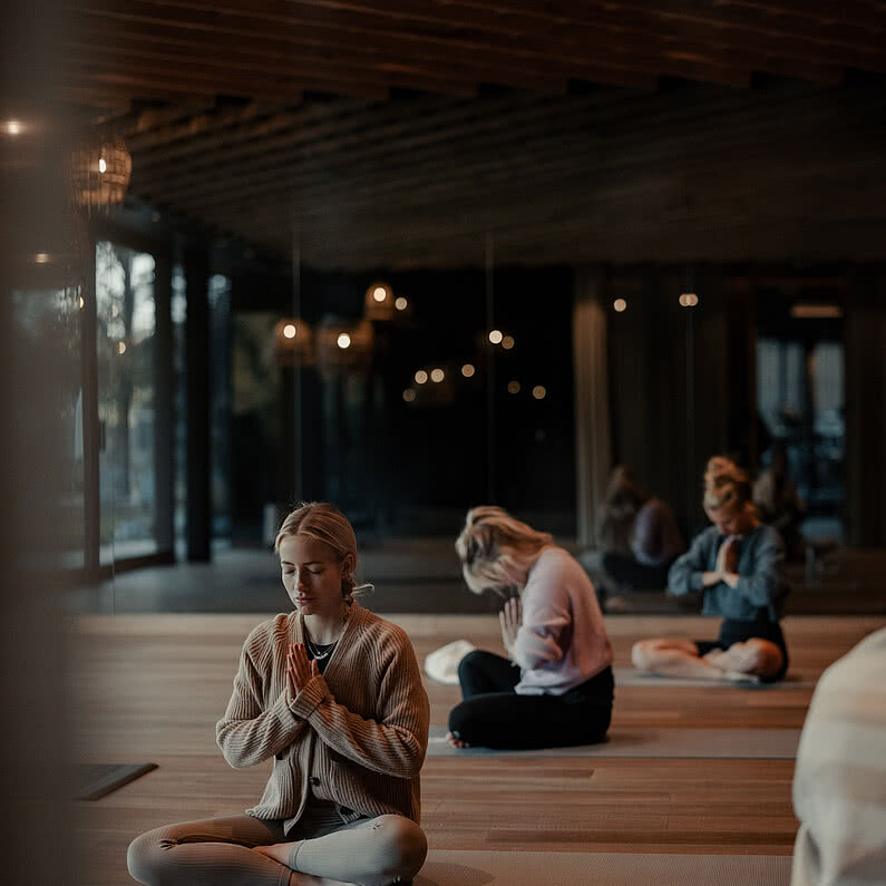 Frauen in Meditation im Yoga-Raum des Genussdorfs Gmachl, in entspannter Atmosphäre mit Fokus auf Achtsamkeit und innerer Ruhe.